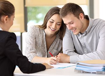 A couple signs paperwork with another person