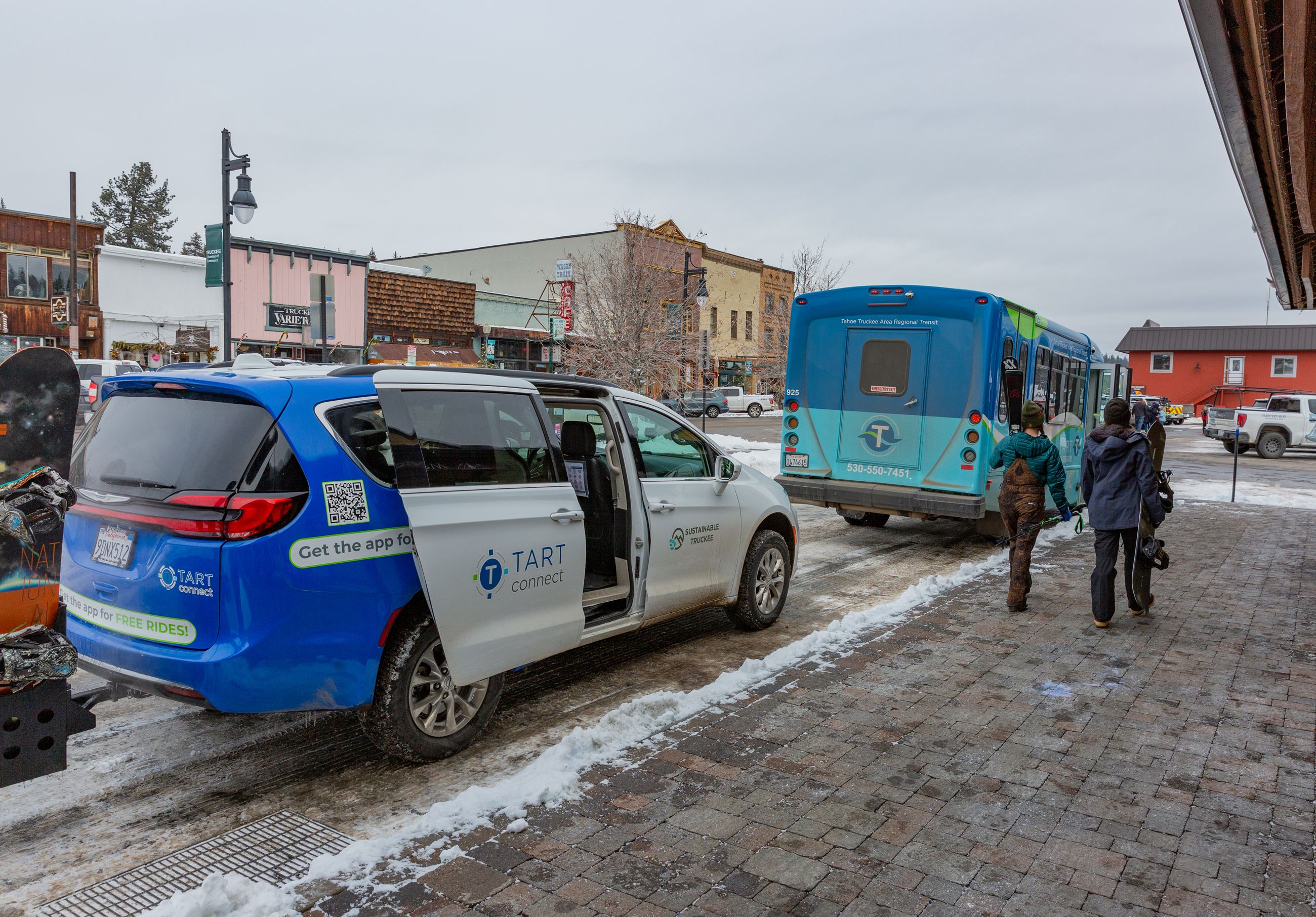 Shuttle van and bus lined up at a snowy transit station.  