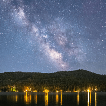 Stars bright in the night sky over Donner Lake with housing lights reflecting on water