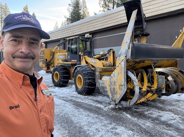 A selfie of Brad Kohler next to a large snow removal machine. 