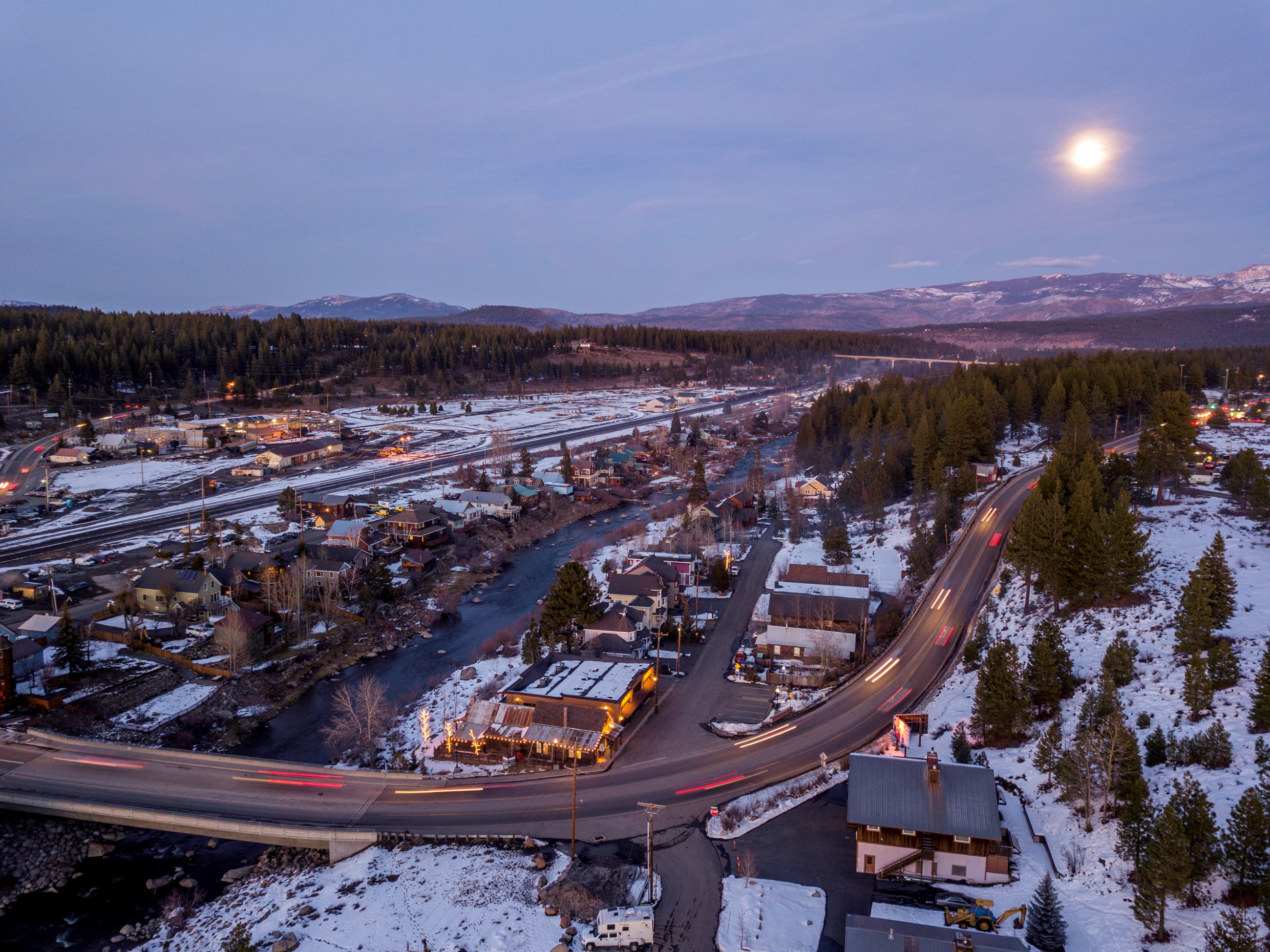 Photo from birdseye view of Downtown Truckee and Truckee River in the early evening with snow. 