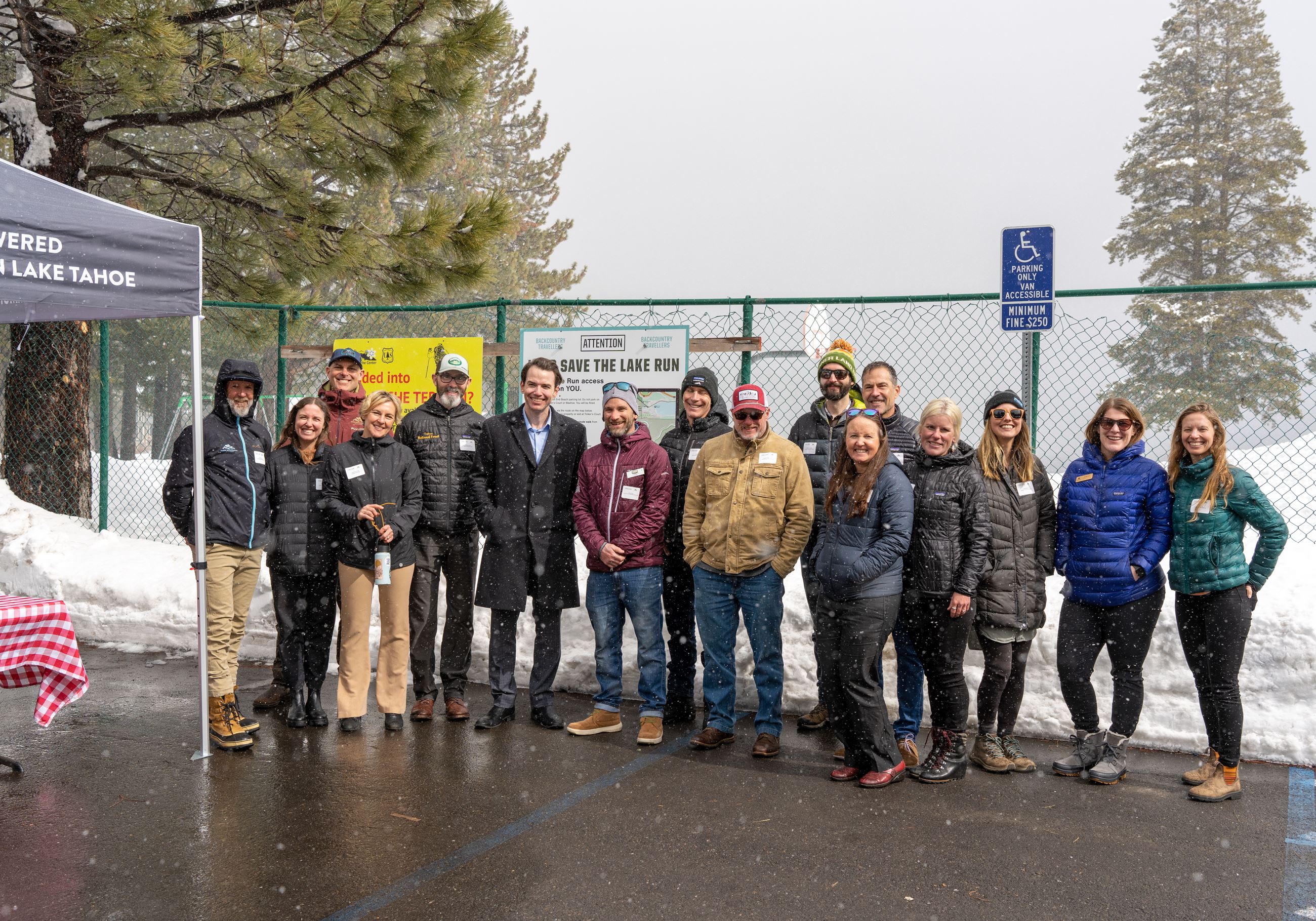 Group of people standing in a paved parking lot in the snow. 