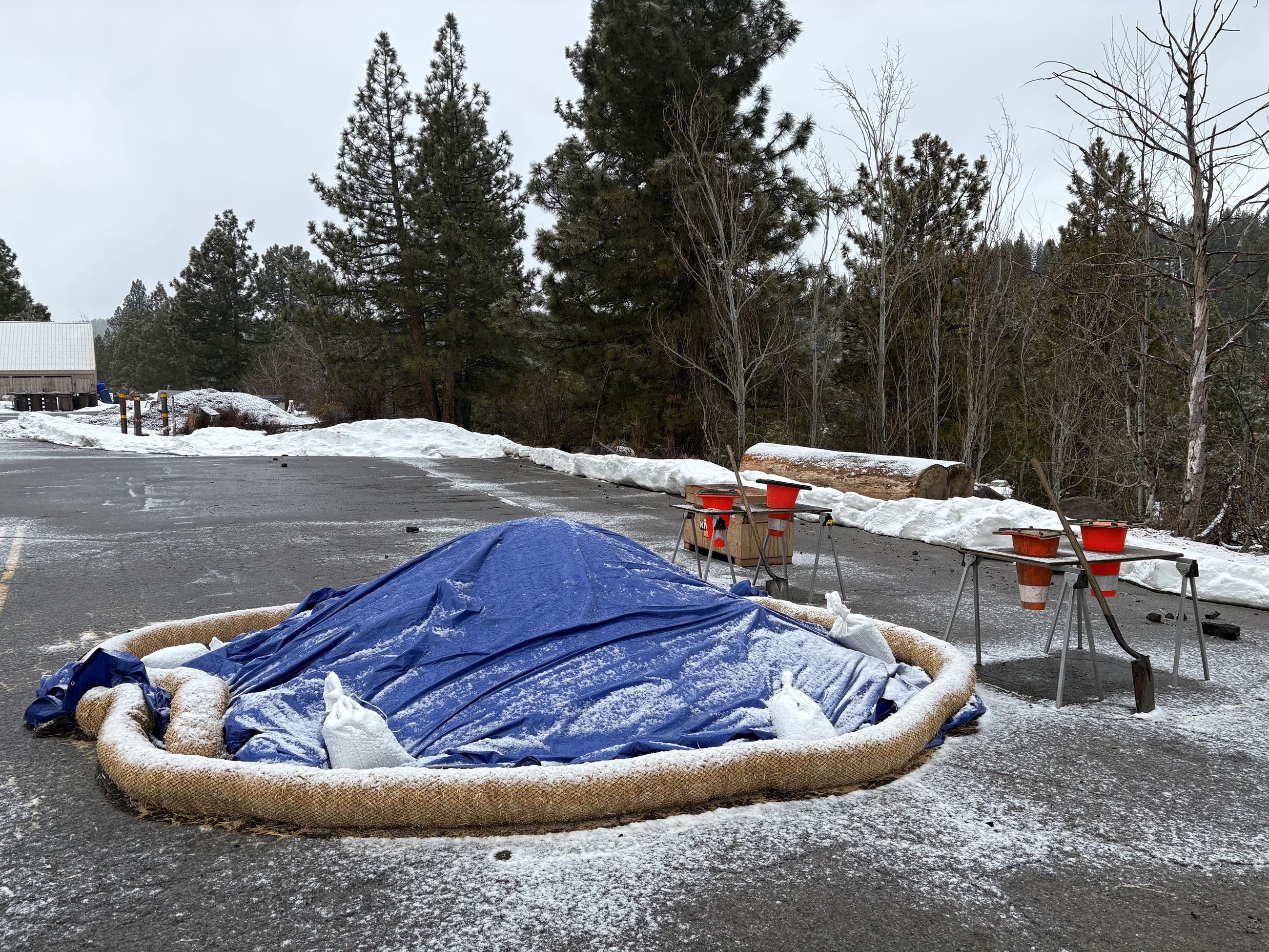 Sandbag location with sand pile covered by a tarp with a dusting of snow. 