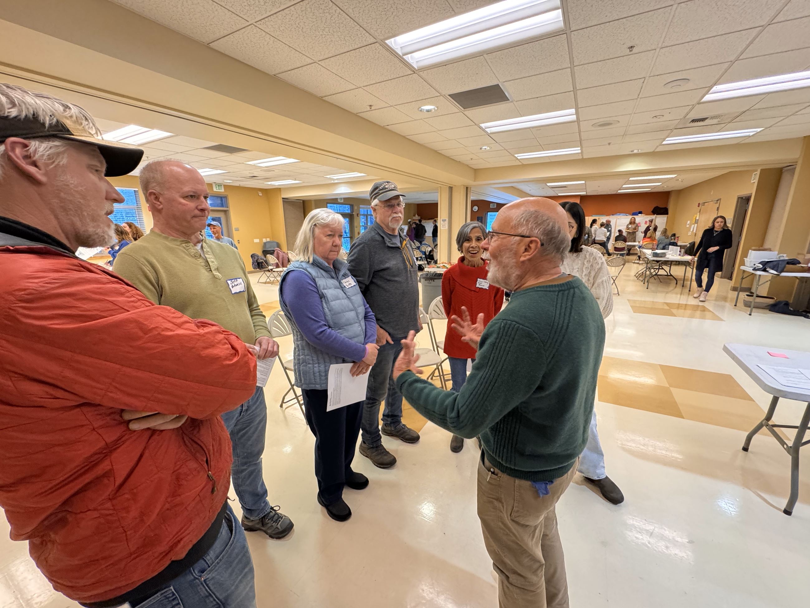 people circled around a person talking at a community workshop. 