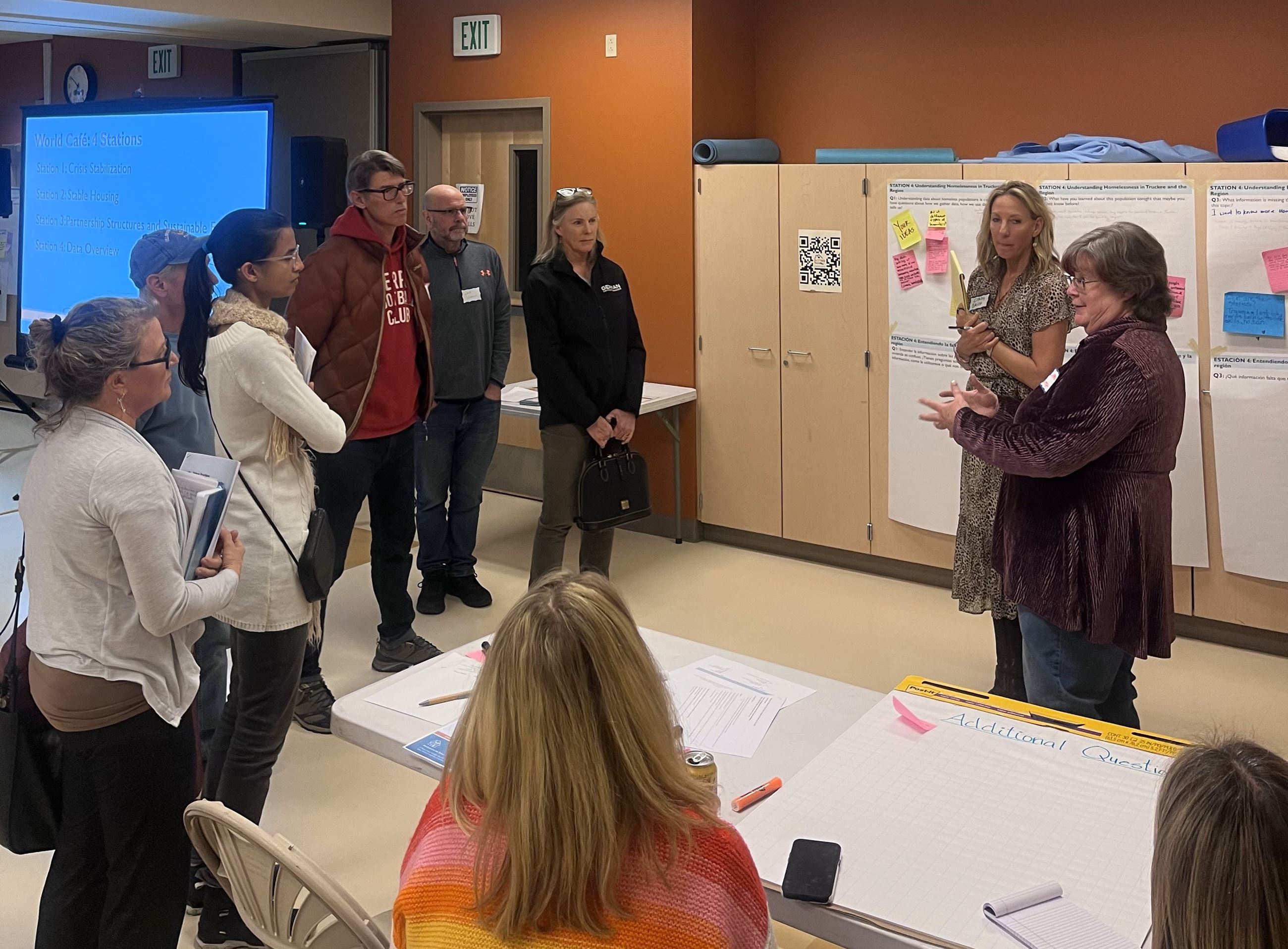 people circled around a person talking at a community workshop. 
