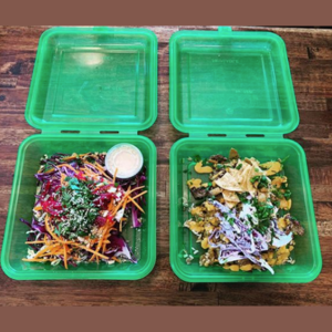 two meals displayed in green reusable containers.